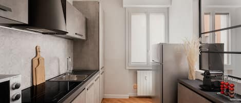 A modern kitchen with a black stove, white cabinets, and a wooden cutting board.