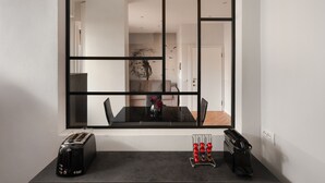 A modern kitchen with a large window, a toaster, a coffee maker, and a fruit basket on the counter.