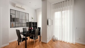 A modern dining area with a black table and chairs, a large mirror, and a TV on the wall.