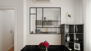 A modern kitchen with a black countertop, a vase with flowers, and a black shelving unit with decorative items.