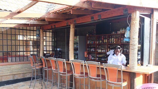 Una zona de bar con taburetes de metal y una barra de madera.