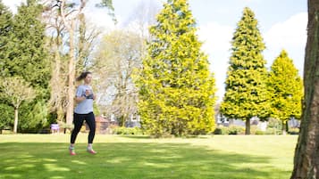 A person jogging in a park with trees and a building in the background.