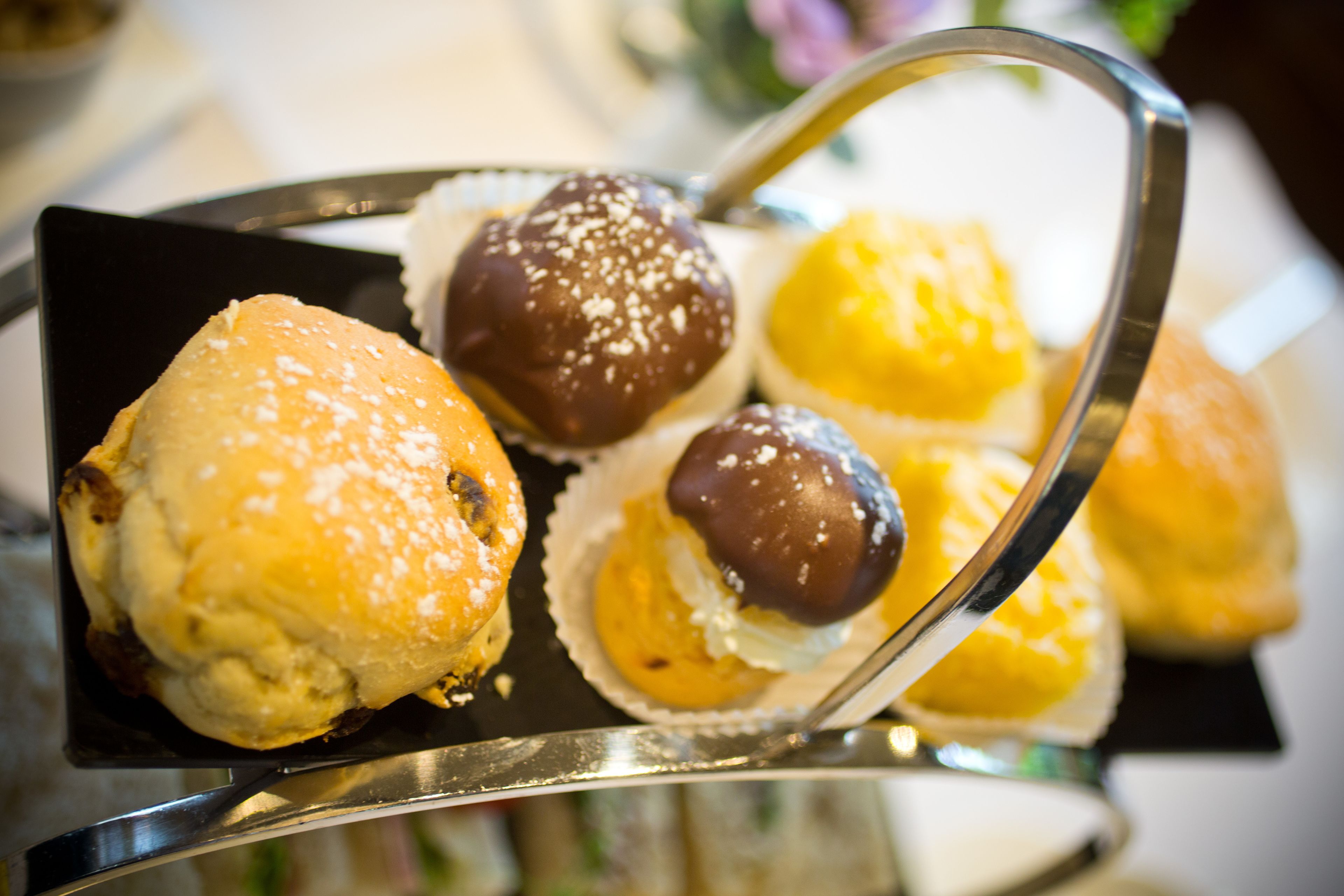Una bandeja de pasteles, incluyendo una bola cubierta de chocolate y un pastel amarillo, sobre un soporte de metal.