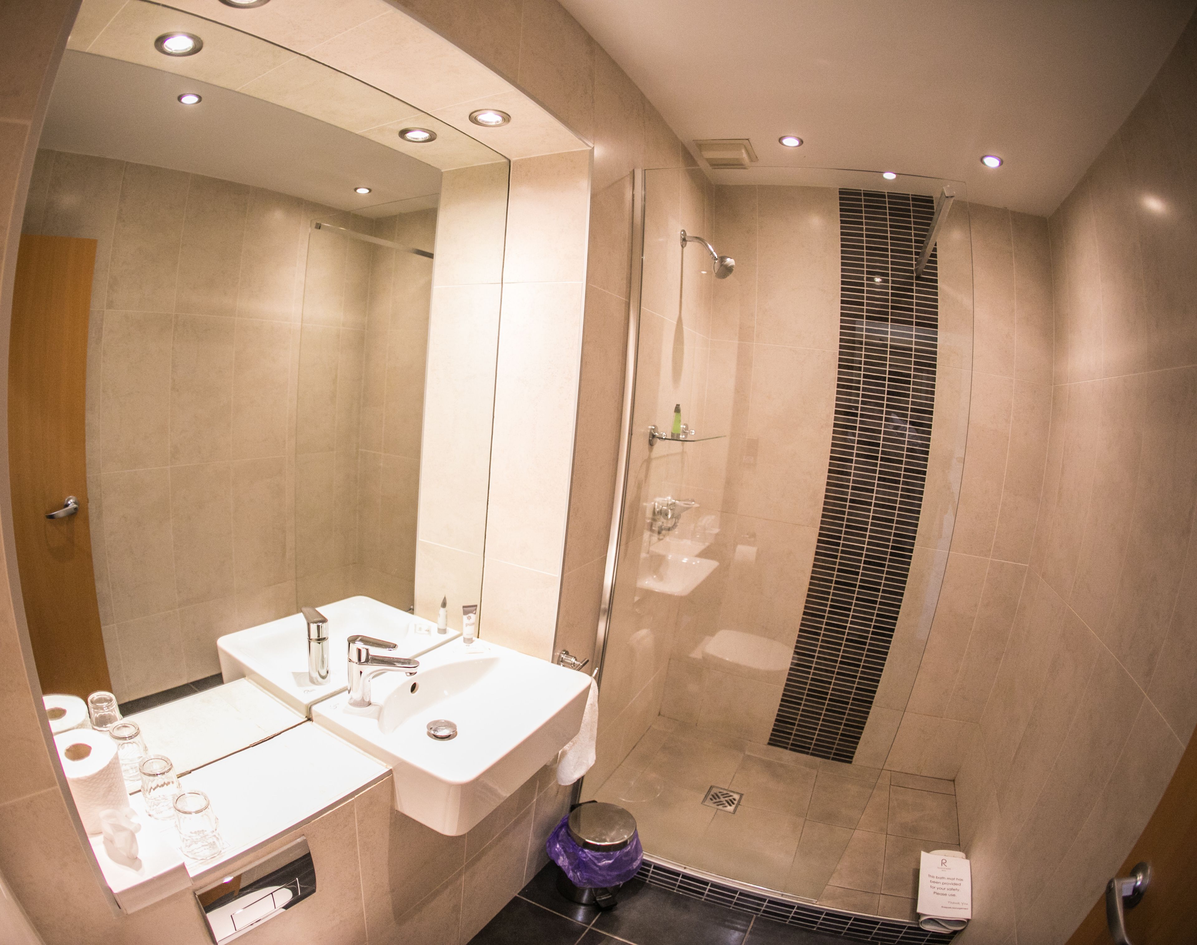 A modern bathroom with a walk-in shower, a vanity with a mirror, and a toilet.