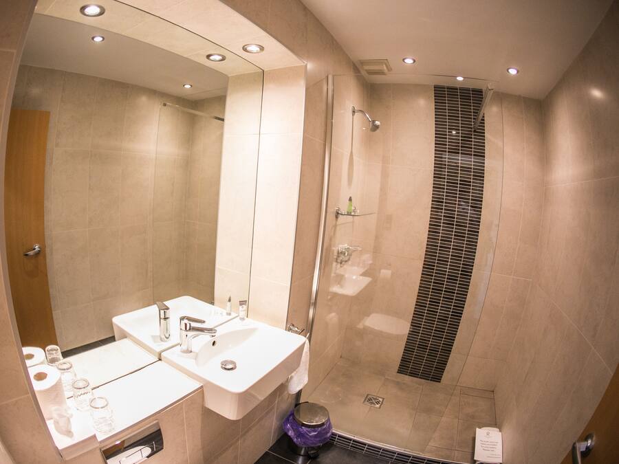 A modern bathroom with a walk-in shower, a vanity with a mirror, and a toilet.