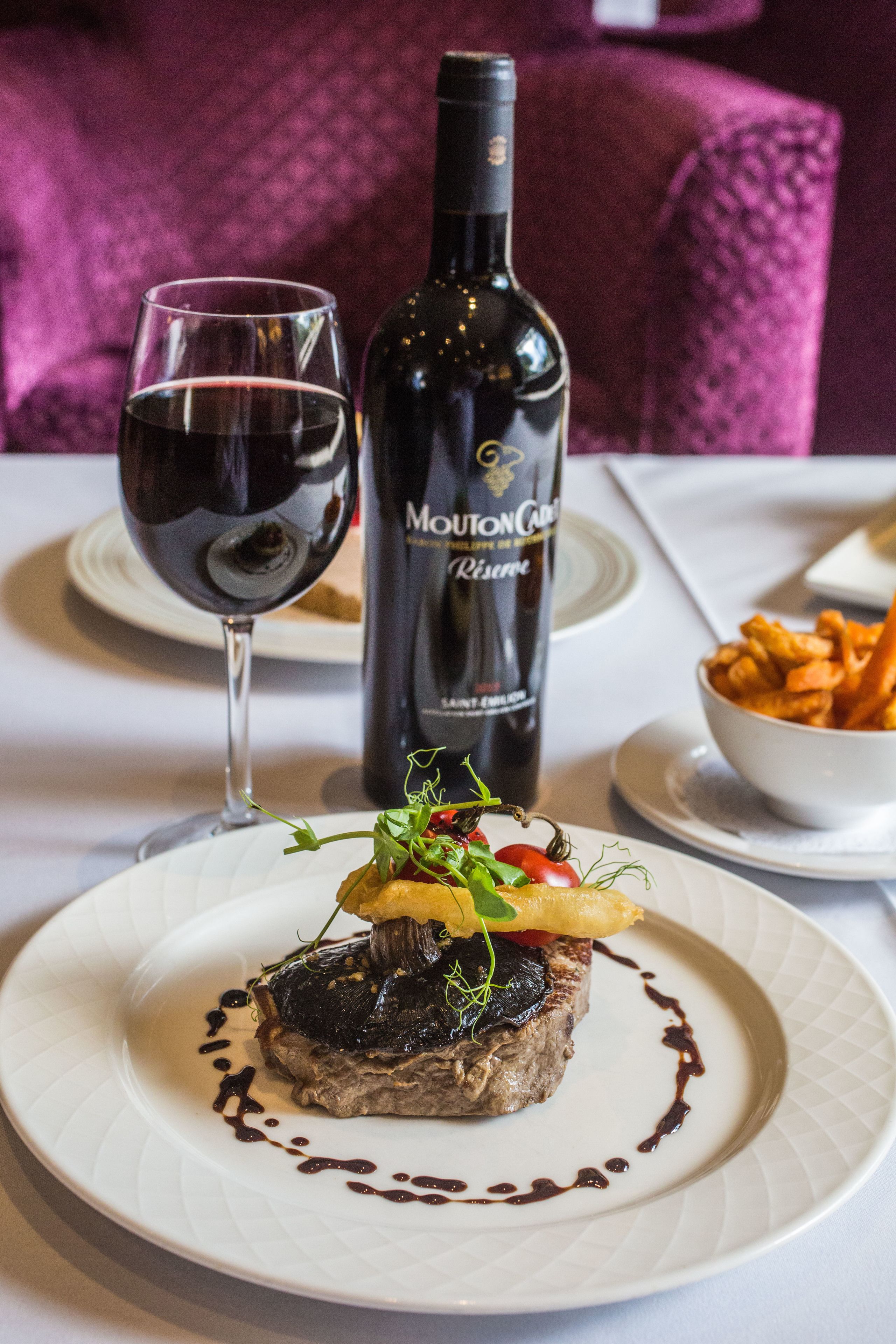 Un plato de comida con una botella de vino y una copa sobre una mesa.