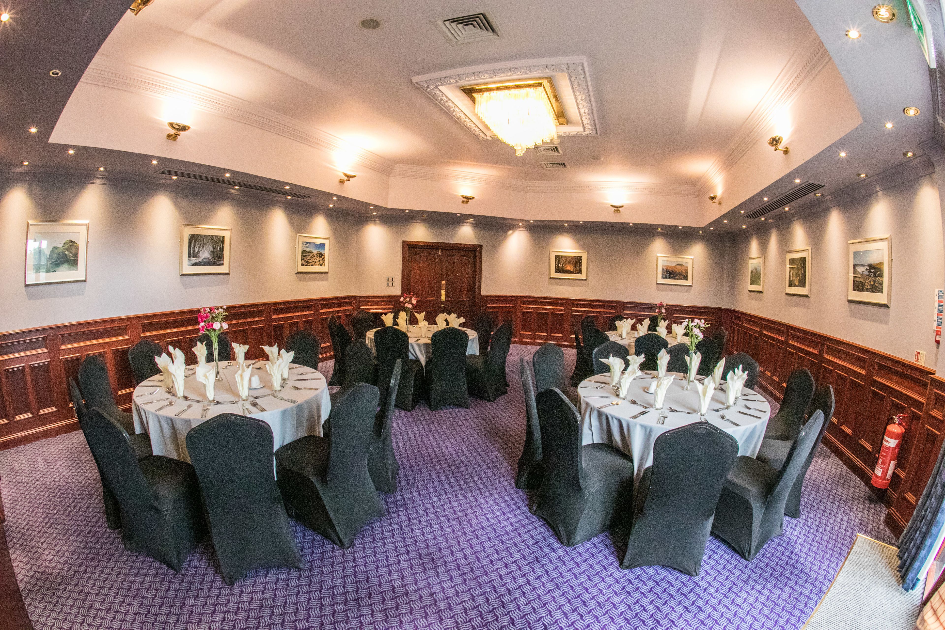 A conference room with round tables, black chairs, and purple carpeting.