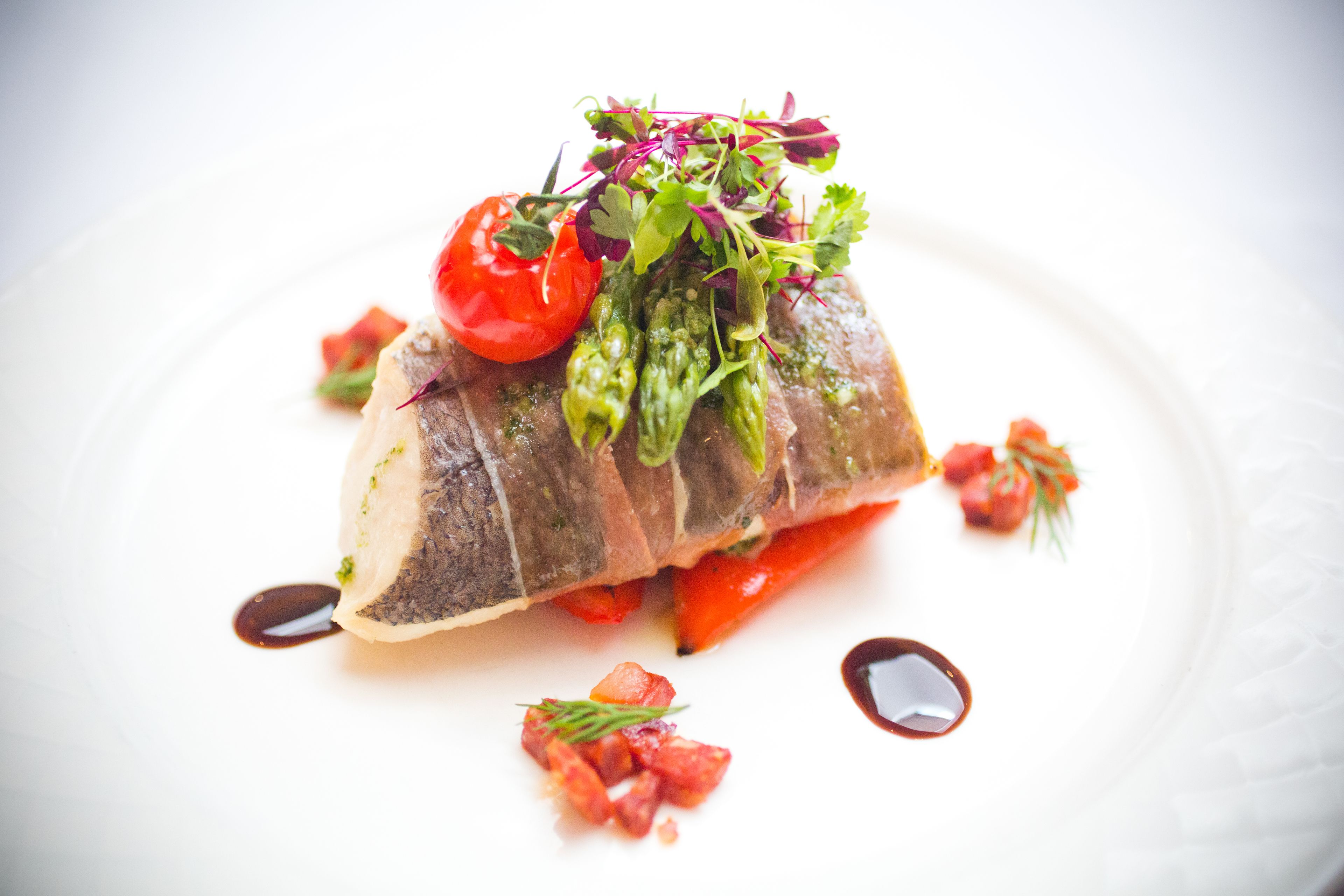 Un plato con pescado, verduras y salsa.