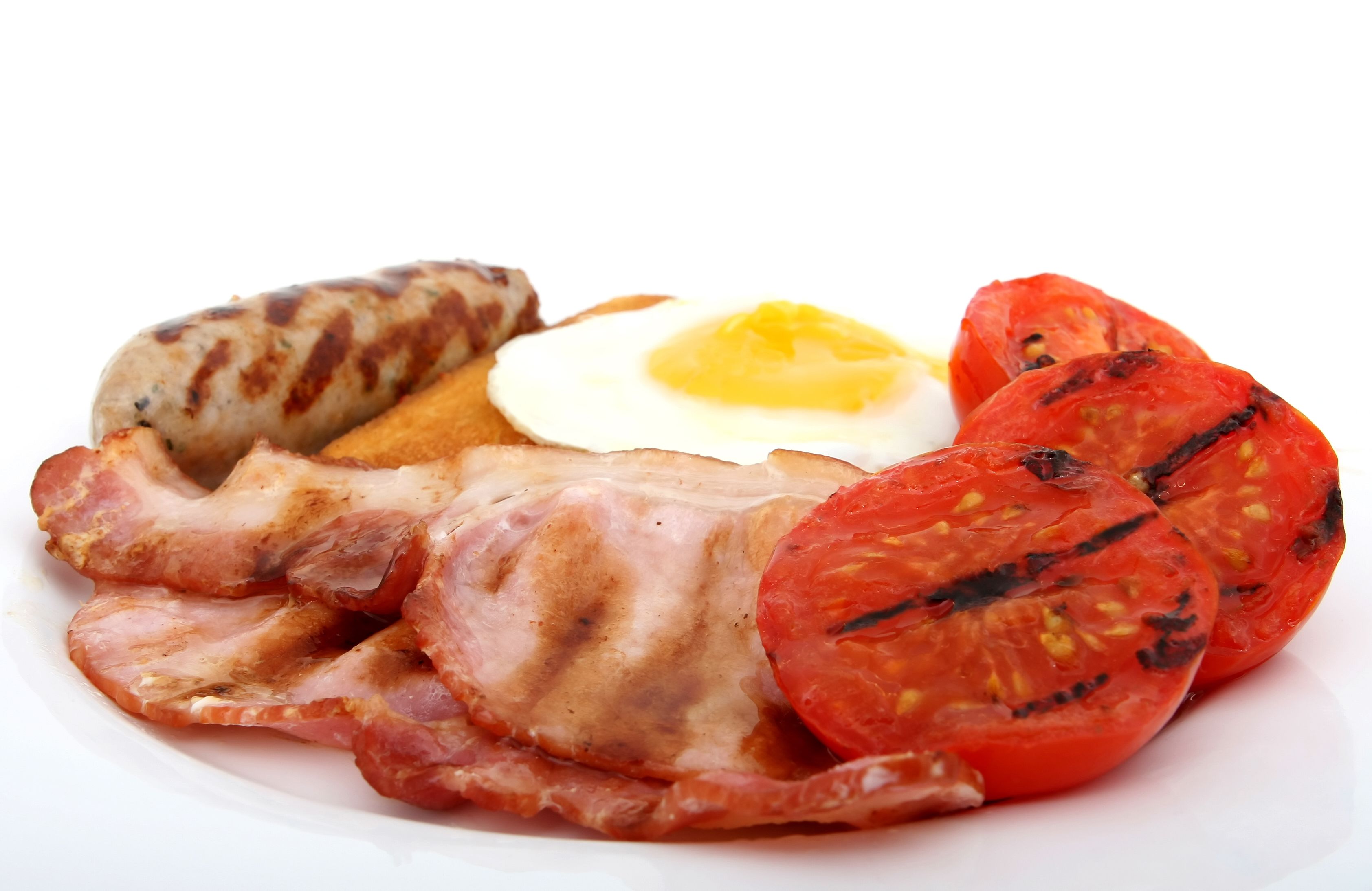 Ein Teller mit gegrillten Würstchen, Speck, einem Spiegelei und gegrillten Tomaten.