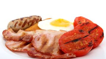 Ein Teller mit gegrillten Würstchen, Speck, einem Spiegelei und gegrillten Tomaten.