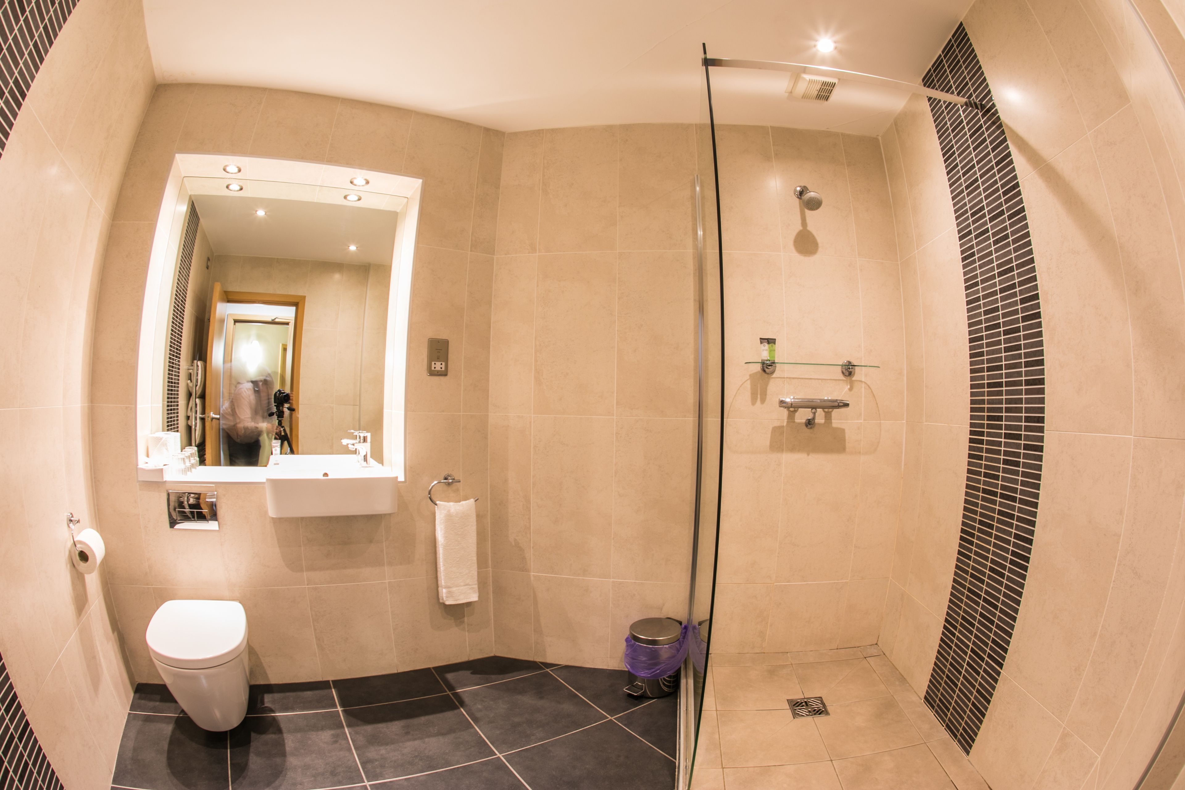 A modern bathroom with a glass-enclosed shower, a sink with a mirror, and a toilet.