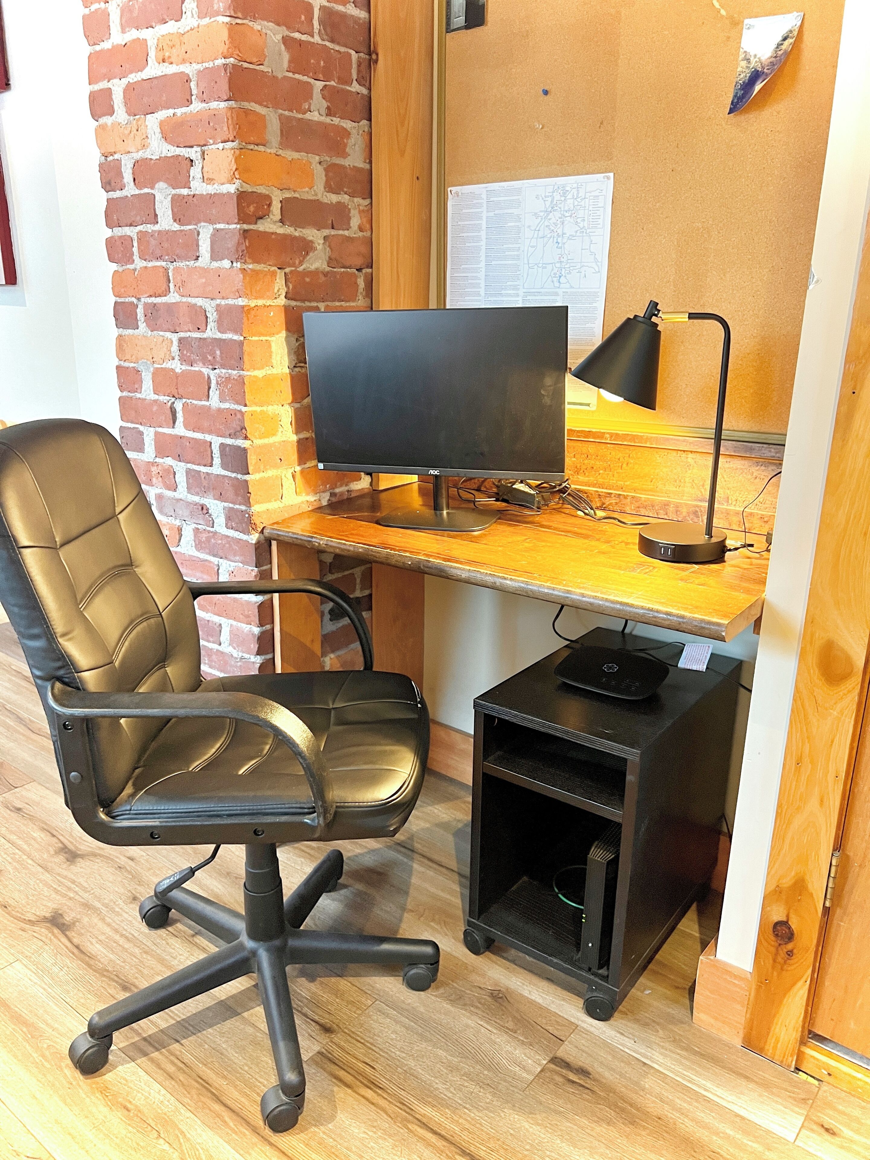 A workspace with a desk, computer, chair, and a small cabinet.
