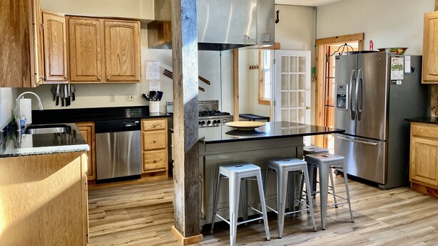 Una cocina moderna con armarios de madera, electrodomésticos de acero inoxidable y una isla central con taburetes.