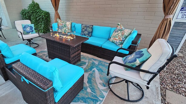 A patio area with wicker furniture, a fire pit, and a glass table.