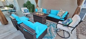 Un espace patio aménagé avec des meubles en osier, un foyer et une table en verre.
