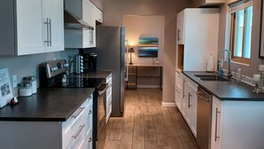 Una cucina moderna con elettrodomestici in acciaio inossidabile, pavimento in legno e un'isola centrale.