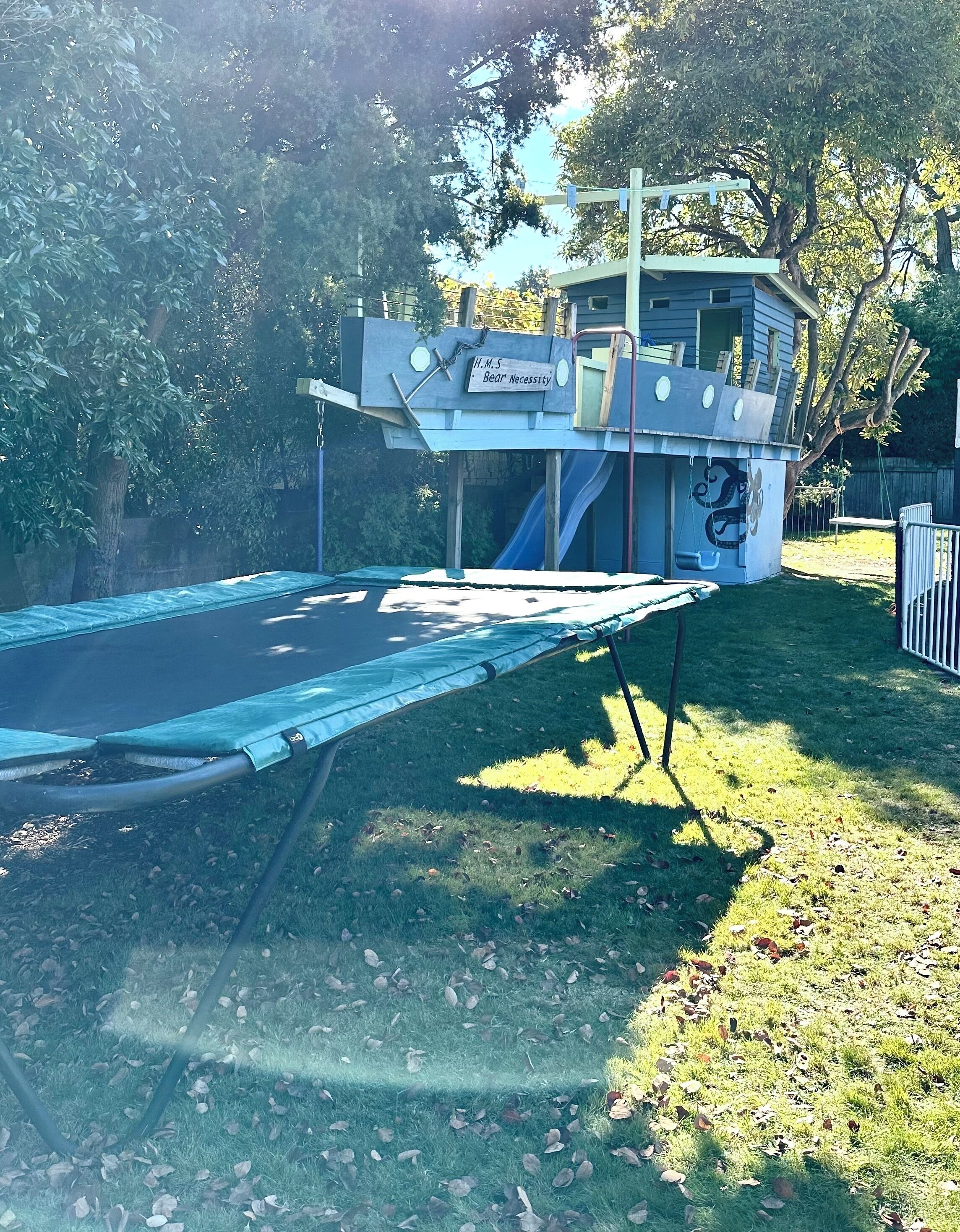 A trampoline in a grassy area with a small building labeled 'H.M.S. Bear Necessity.'