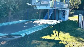 A trampoline in a grassy area with a small building labeled 'H.M.S. Bear Necessity.'