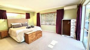 Une chambre à coucher avec un lit, des tables de chevet, une armoire et une fenêtre avec des rideaux.