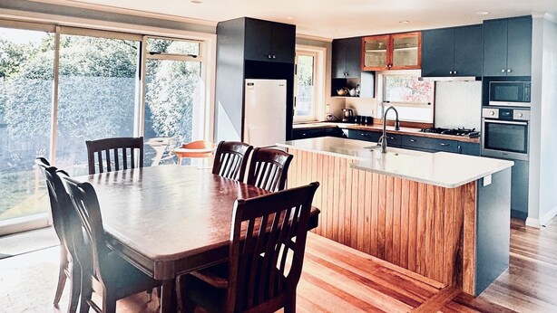 Une cuisine moderne avec un îlot central, une table à manger en bois et des chaises.
