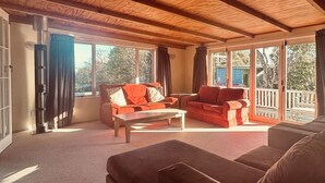Un salon chaleureux avec un plafond en bois, un canapé, un divan rouge et une table basse.