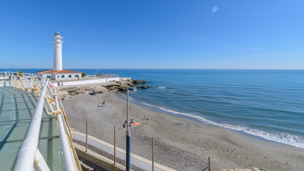 A coastal scene with a lighthouse, beach, and a pier. - Moorish-Style Mountain Villa: Stunning 360° Views, Pool & Hot Tub (Torrox)
