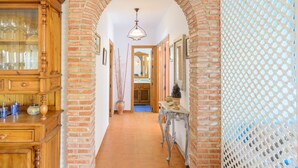A hallway with a brick archway, a wooden cabinet with glass doors, and a patterned wall. - Moorish-Style Mountain Villa: Stunning 360° Views, Pool & Hot Tub (Torrox)