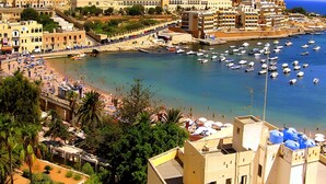 Un pueblo costero con un puerto deportivo, edificios y una zona de playa.