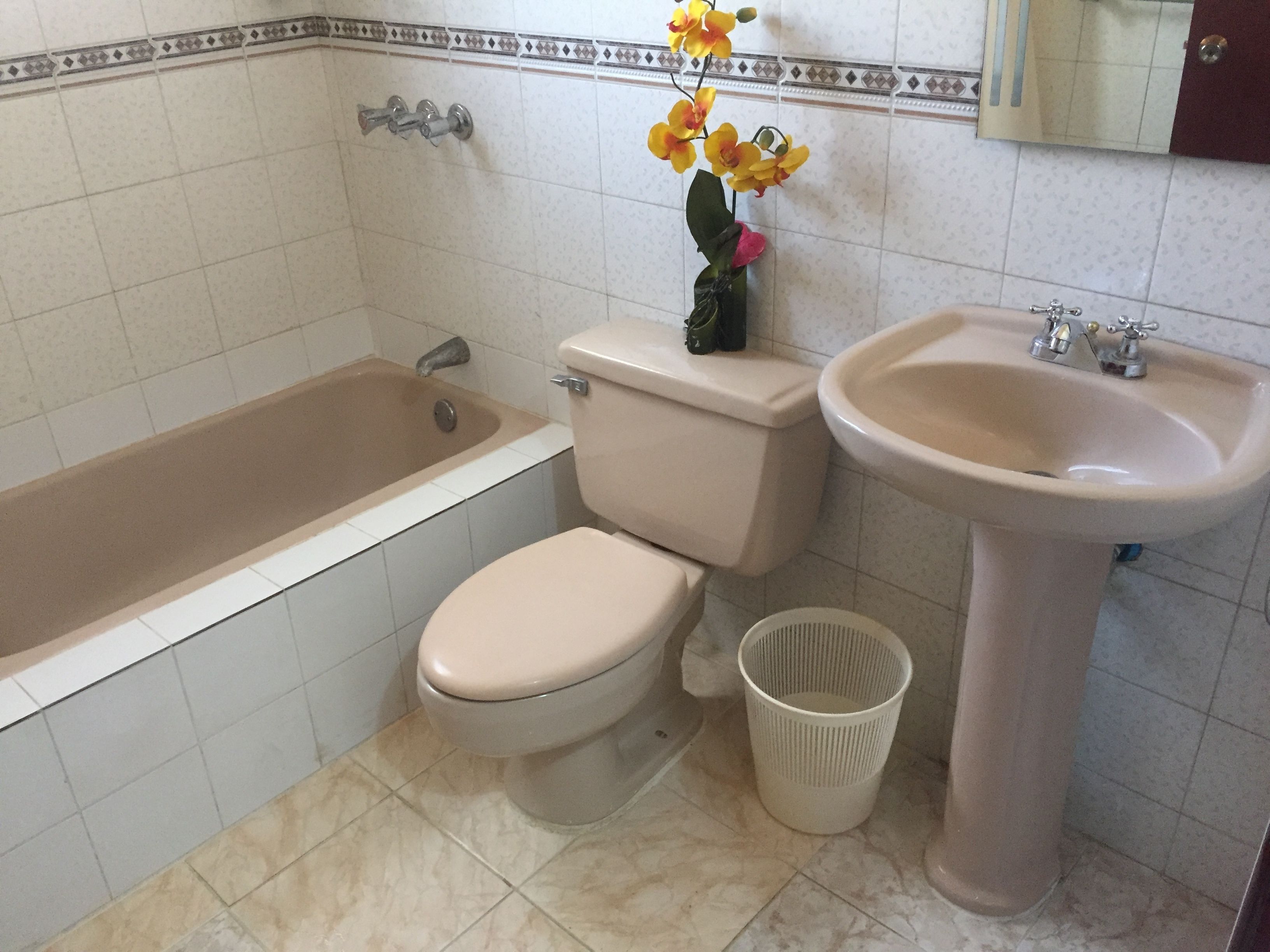 A bathroom with a bathtub, toilet, sink, and a trash bin.