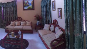 A living room with a sofa set, a coffee table, a cabinet, and a staircase. - Nicole's Guest Home (Higuey)