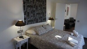 A neatly made bed with a patterned bedspread, two bedside lamps, and a large abstract wall art piece. - ATTIC + PRIVATE TERRACE AND FREE WIFI (Sevilla)
