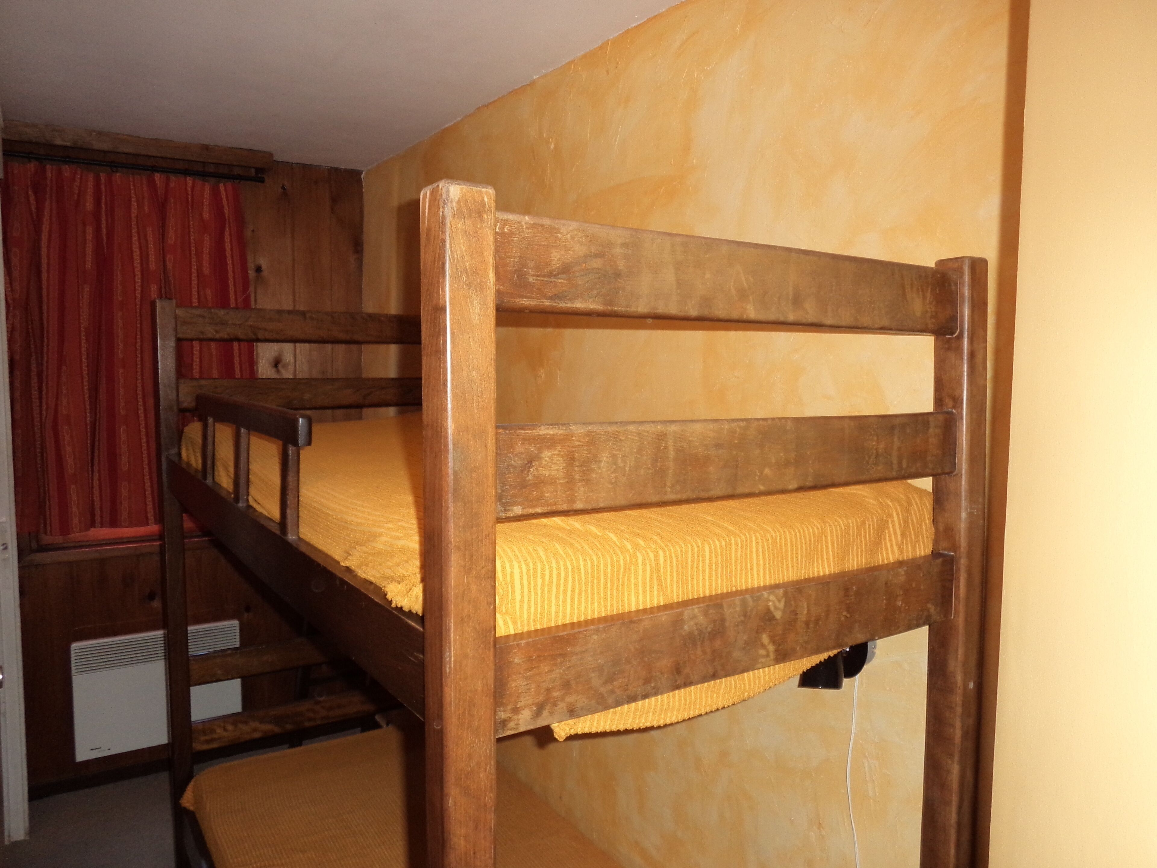 A bunk bed with a wooden frame and a yellow mattress.