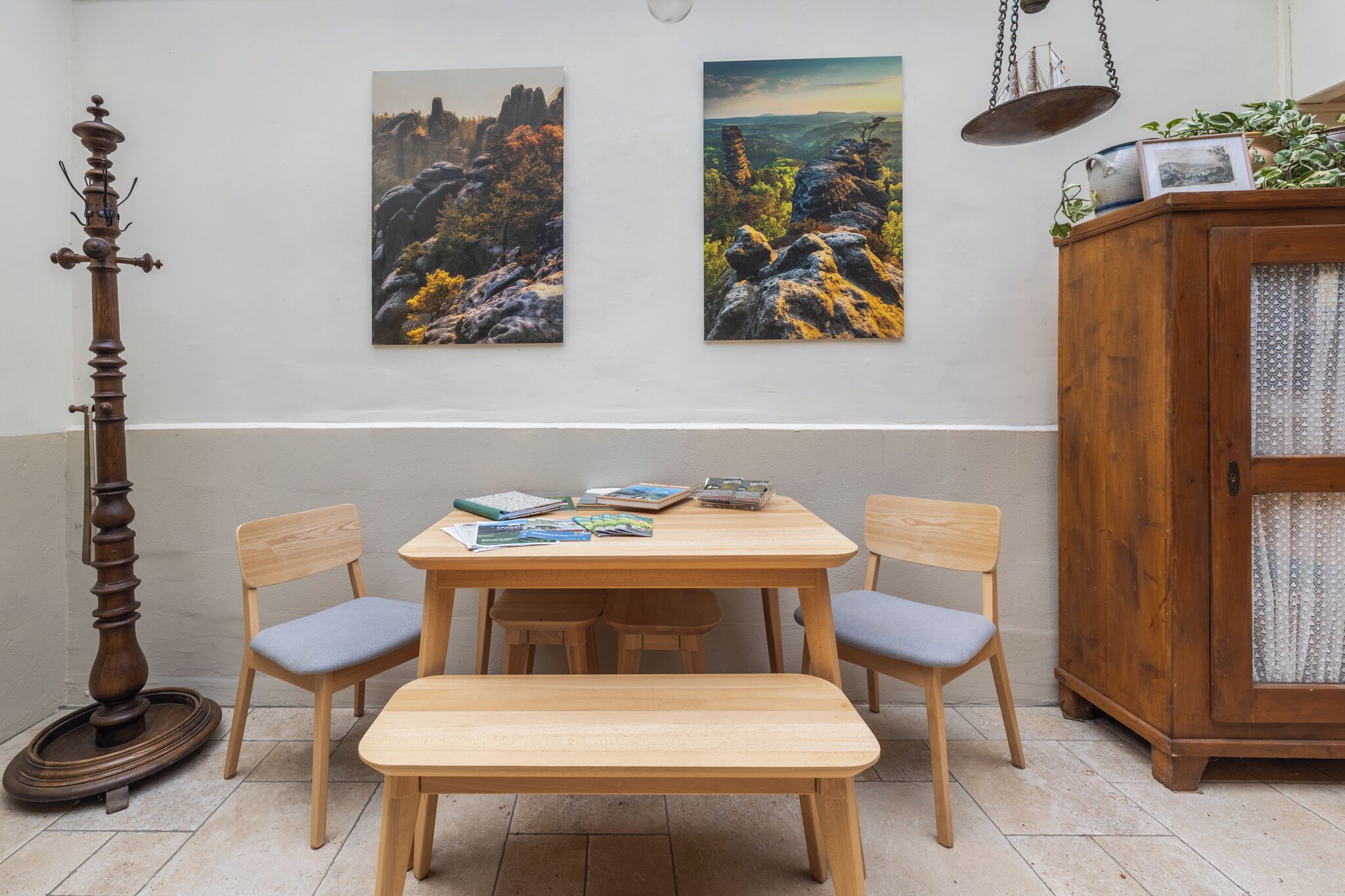 Ein Essbereich mit einem Holztisch, Stühlen, einem Holzschrank und zwei Landschaftsbildern an der Wand.