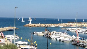 A marina with boats docked, a rocky breakwater, and sailboats in the distance. - Nice apartment in a character villa next to the sea in Banyuls (Banyuls-Sur-Mer)