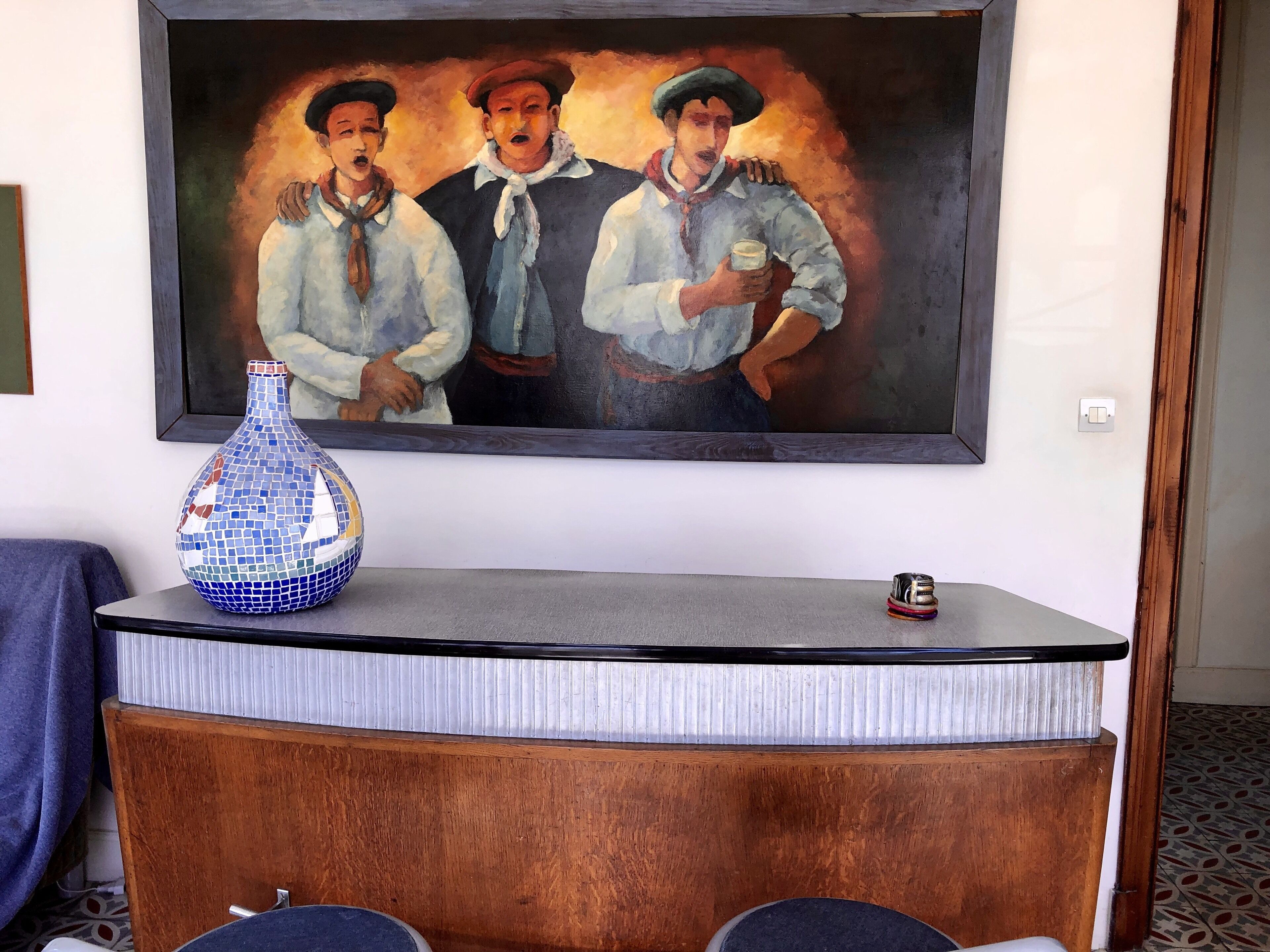 A reception desk with a mosaic vase, a framed painting, and a small decorative item.