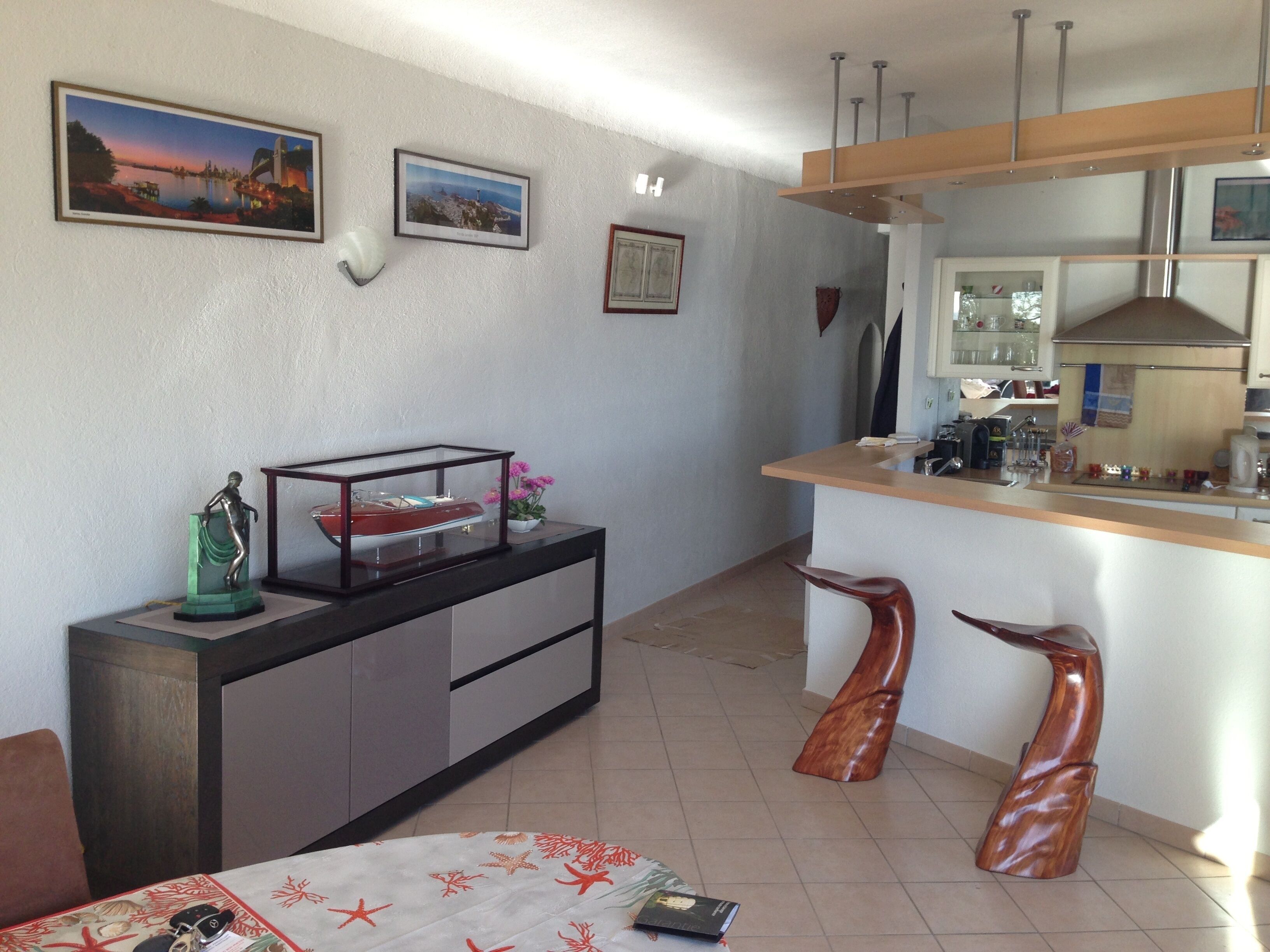 Una cocina compacta con una isla central, un comedor con mesa y sillas, y un pequeño rincón de estar con sofá.