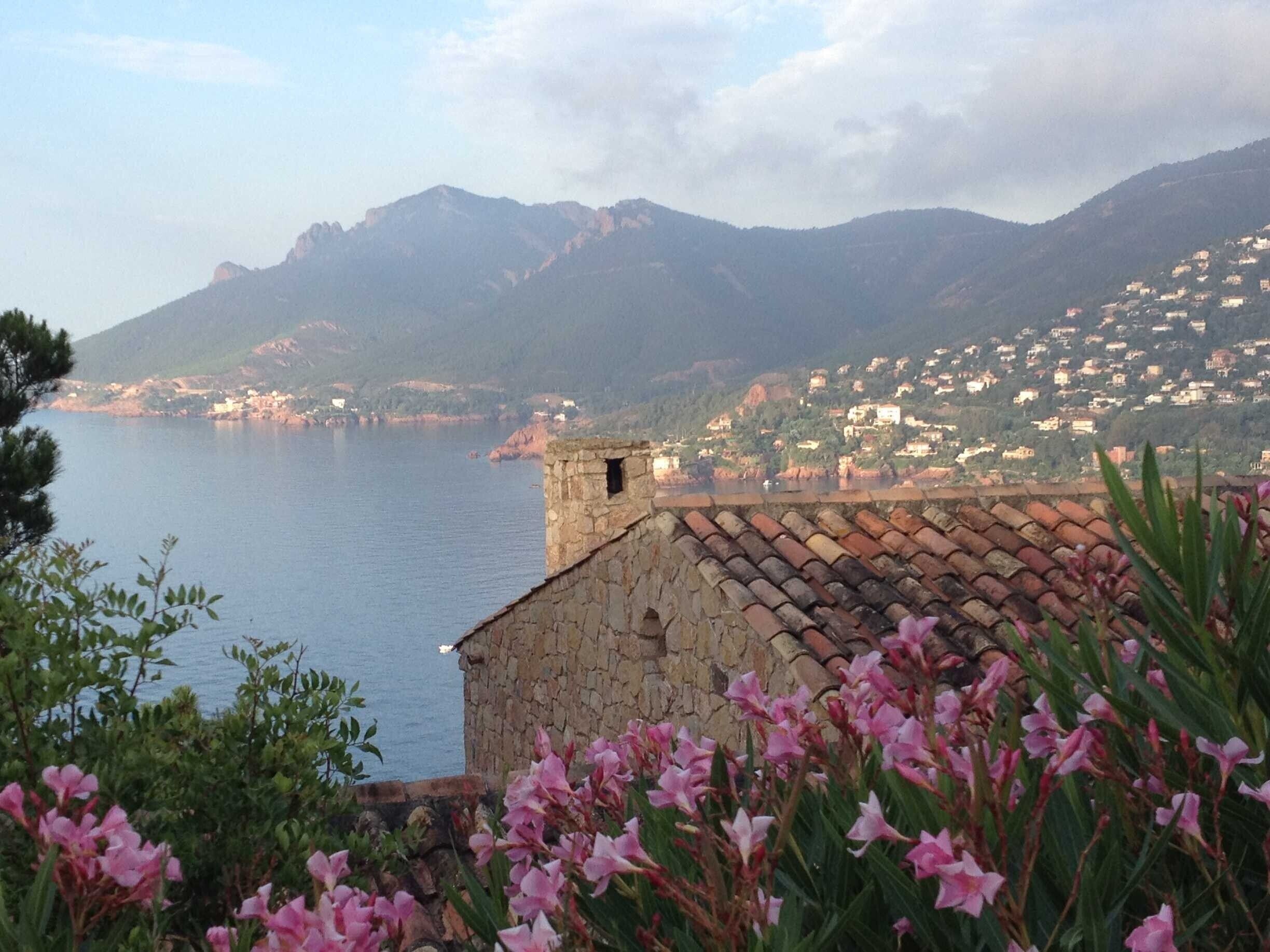 A coastal town with stone buildings and a view of the sea and mountains.