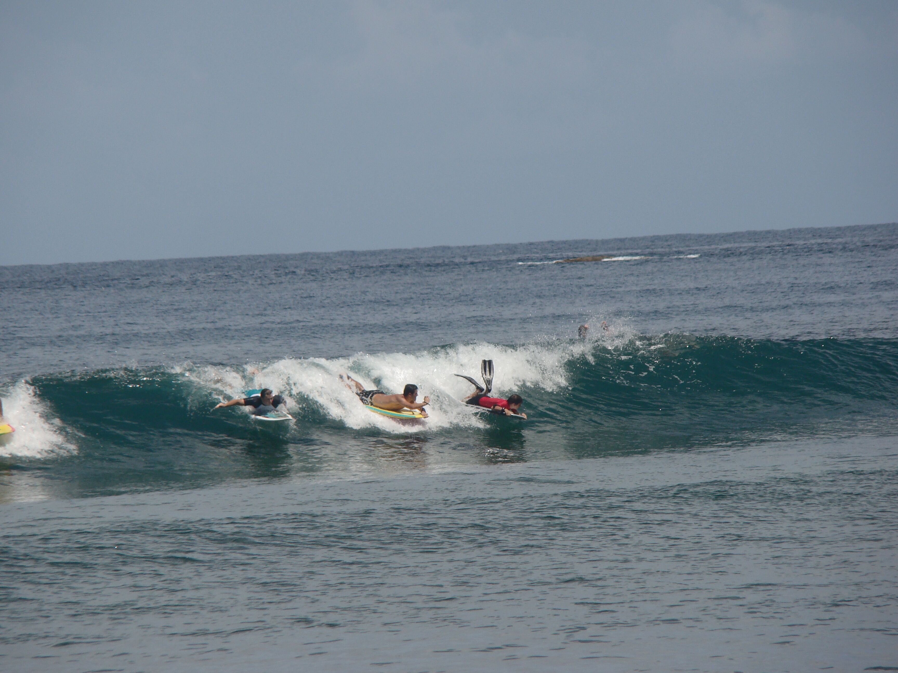 A group of surfers riding waves in the ocean.