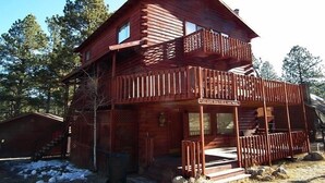 Eine zweistöckige Blockhütte mit Balkon, Veranda und einem sichtbaren Schild.