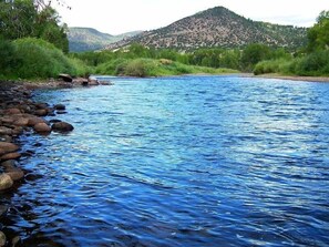 Een rivier met helderblauw water, omringd door groene begroeiing en een berg op de achtergrond.