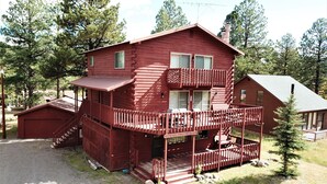 Eine zweistöckige Blockhütte mit Balkon und separater Garage.