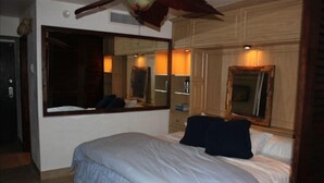 A bedroom with a large bed, a mirror, and a wooden headboard. - Sapphire Beach is just a few steps out your door!!! (St. Thomas)