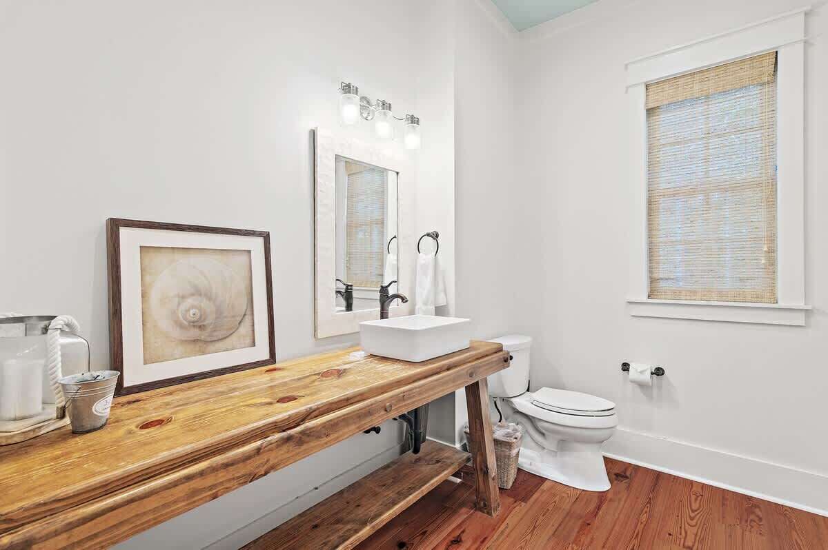 A bathroom with a wooden vanity, a white sink, a mirror, and a toilet.