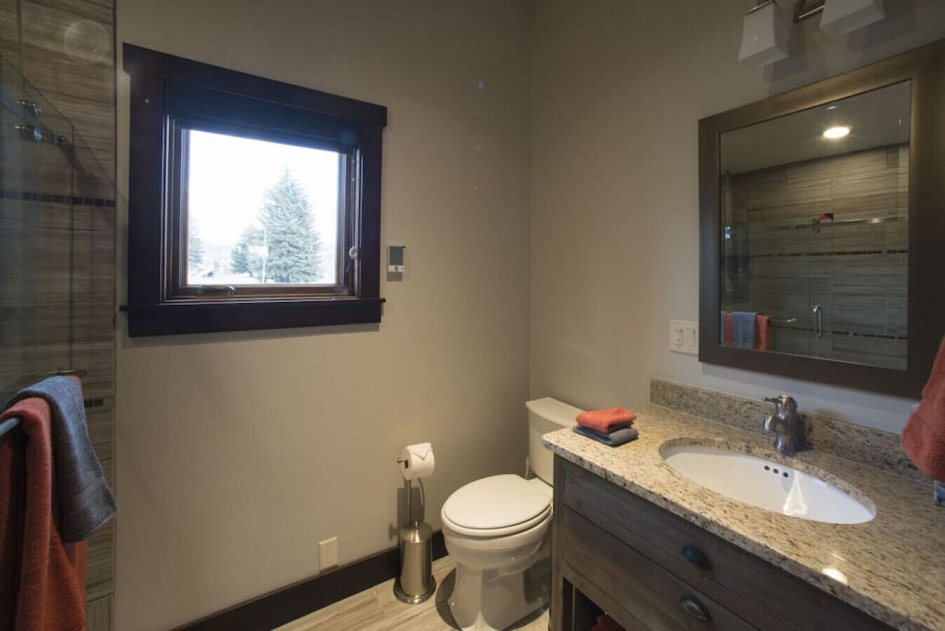 Une salle de bain moderne avec une fenêtre, des toilettes, un lavabo et un miroir.