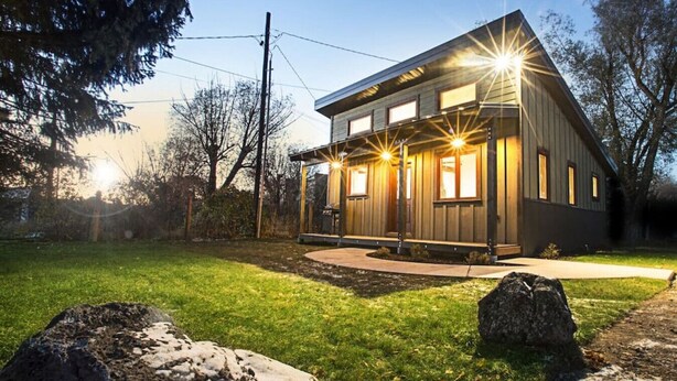 A modern two-story house with a well-maintained lawn and a large rock in the foreground. - Modern Cabin with Walkability in Downtown Driggs (Driggs)