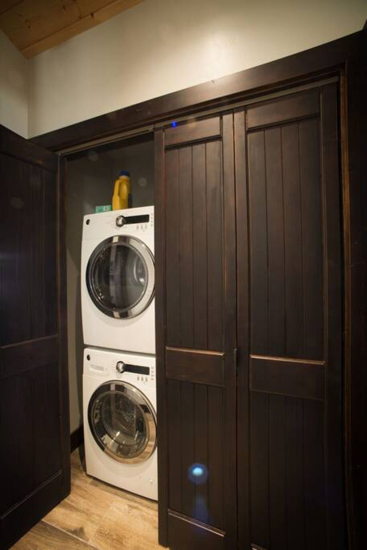 Ein Waschraum mit zwei übereinander gestapelten Waschmaschinen mit Frontöffnung und einem dunklen Holzschrank.