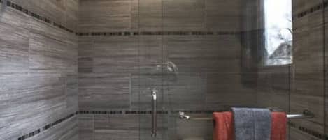 A modern bathroom with a glass-enclosed shower, a bathtub, and a towel rack with a towel.