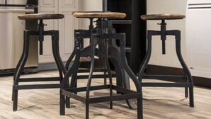 A kitchen with white cabinets, a central island with stools, and a black metal staircase. - Modern Cabin with Walkability in Downtown Driggs (Driggs)