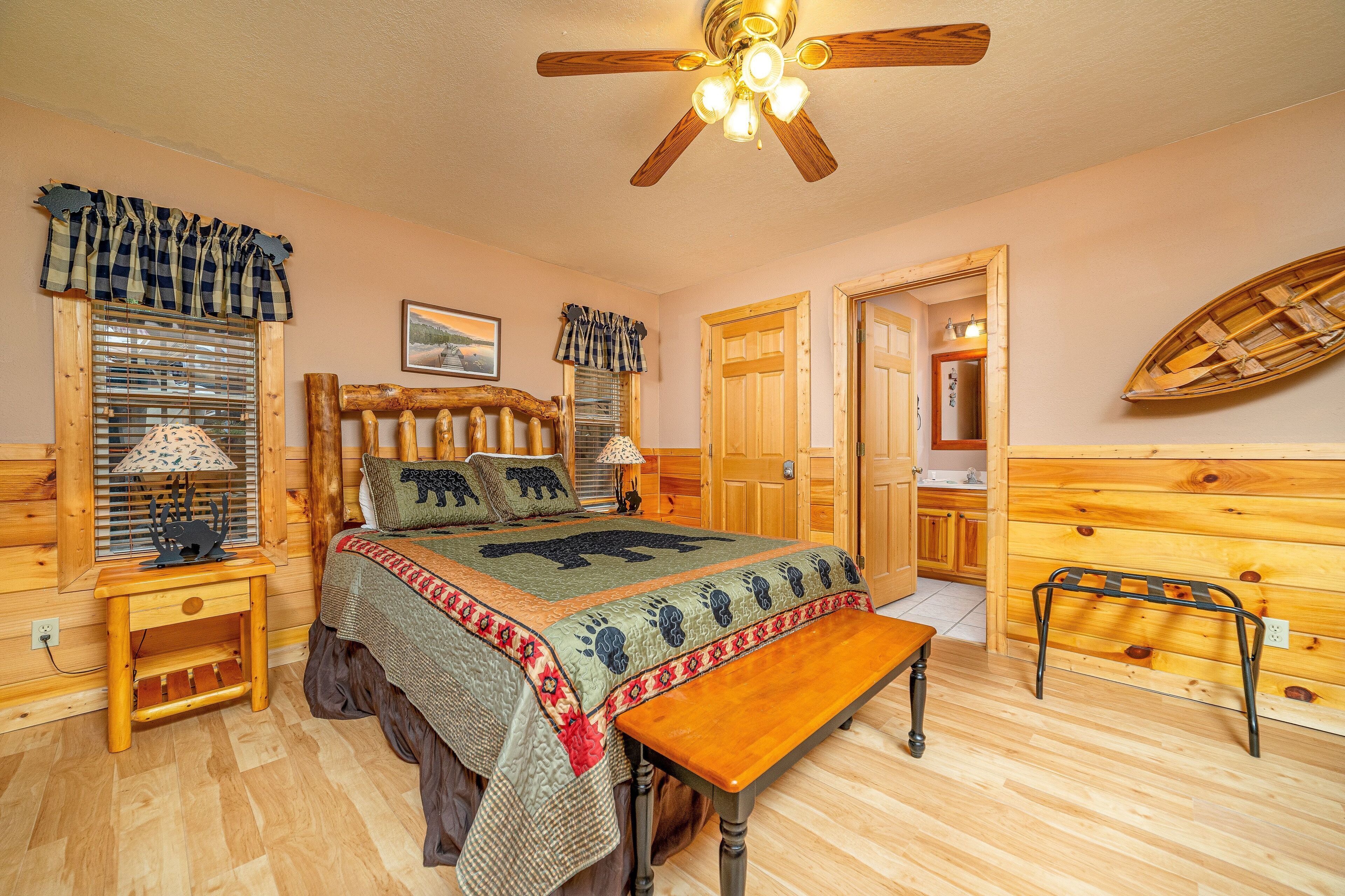 Un dormitorio acogedor con una cama de madera, un banco, un ventilador de techo y una decoración con forma de barco de madera.