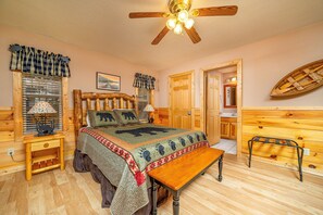 Une chambre confortable avec un lit en bois, un banc, un ventilateur de plafond et une décoration représentant un bateau en bois.